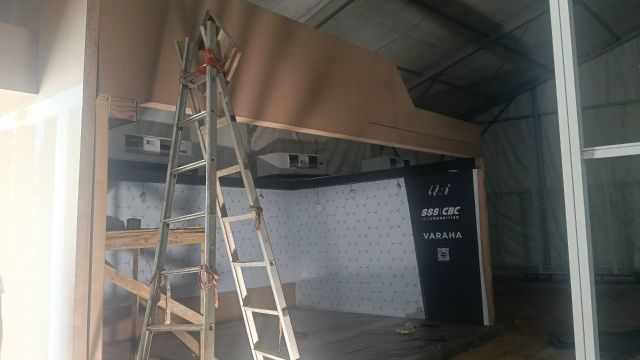 FICCI 2026 stall under construction: a ladder in front of the hexagon wall and a navy SSS CBC and Varaha panel already installed